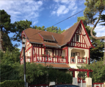 Vue en couleur d'une maison anglo-normande aux boiseries extérieures rouges.