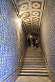 Escalier en marbre blanc menant à l'étage noble. Le plafond est de style italien, ainsi que les céramiques murales.