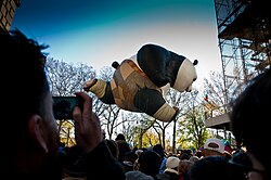 A massive parade balloon of Po from the Kung Fu Panda series looms over a crowd at the Macy's Thanksgiving Day Parade of 2011.