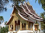 Stone building with golden decorated entrance, stacked and very steep roofs.