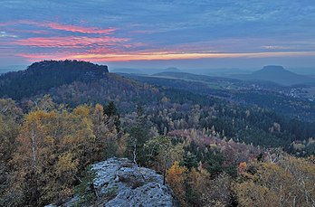 Coucher de soleil dans le parc national de la Suisse saxonne, en Allemagne. Vue depuis le sommet de la Papststein. Les trois grandes montagnes sont le mont Gohrisch (à gauche), le mont Königstein (au centre) et le mont Lilienstein (à droite). Le village s'appelle Gohrisch. (définition réelle 2 780 × 1 831)