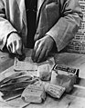 Rationnement des civils : Un commerçant britannique oblitère des tickets de rationnement en avril 1943.