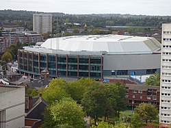 White and grey circular building with trees in the foreground.