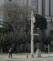 A square utility pole with an ornamental streetlight