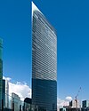 Ground-level view of a thin high-rises's curved, glass facade