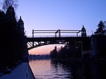 A bridge with Collegiate Gothic style towers over a canal at sunset