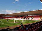 Inside an almost-empty modern stadium whose coloured seats spell out the initials D F C and the word Darlington. Players appear to be warming up on the pitch.