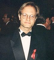 Photographie du buste d'un homme portant des lunettes et habillé en tenue de soirée.