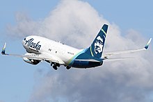 A plane painted with the words "Alaska Air Cargo" across it takes off