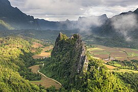 Green karst peaks seen from the top of Mount Nam Xay a sunny morning with fog Vang Vieng Laos