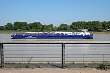 Photographie d'un bateau de faible hauteur bleu. Il transporte une des ailes d'un AirBus.