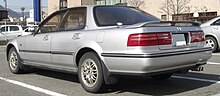 Rear three-quarter view of a four-door car with a three-box body style fitted with a rear spoiler.