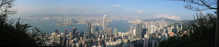 panorama: looking down on a city of skyscrapers, land mass in the distance separated by a body of water