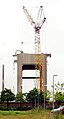 A big mobile crane holding a little digger for demolition of the winding tower of a mine shaft