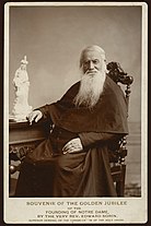 A bearded Edward Sorin sits in a chair at a desk looking at the camera