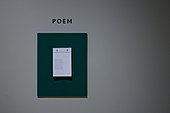 Paper hanging on a white wall with "Poem" written above it