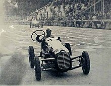 Photo de Tazio Nuvolari, en course à Turin, il tient dans la main droite le volant qui s'est séparé de la colonne de direction.