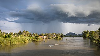 Landscape with stormy clouds and a pirogue on the Mekong at golden hour in Si Phan Don