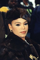 A woman wearing a fluffy black hat and jumper staring directly into the camera