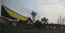 An at-grade station along an avenue and partly below an overpass.