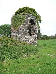 Stump of the round tower at 5.5m high. Various mosses and plants have grown on it, and a large hole sits in it.