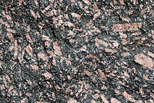 Luxullianite from Cornwall, showing dark patches of tourmaline and pink crystals of orthoclase Luxullianite.jpg