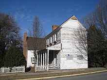 A two-story white wooden house viewed from the street