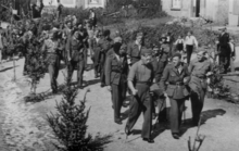 Rapatriement de prisonniers de guerre belges à Chiny avant 1945 (on aperçoit un militaire d'escorte avec un casque allemand à l'arrière plan).