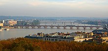 Photographie aérienne du pont de Pierre et de la Passerelle Eiffel. En avant plan, on distingue des arbres aux couleurs rougeatres.