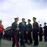 John Fitzgerald Kennedy, escorted by Governor and Commander-in-Chief of Bermuda, Major-General Sir JA Gascoigne, KCMG, KCVO, CB, DSO, DL, and Major JA Marsh, DSO, the Officer Commanding the Bermuda Militia Artillery, inspects a Bermuda Rifles guard in 1961, four years before the units amalgamated