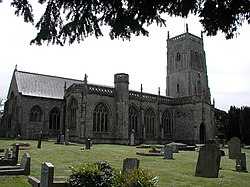 Stone building with prominent square tower. In the foreground are gravestones.