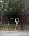 David Eisenhower (age 12), grandson of President Dwight D. Eisenhower, poses with sign at presidential retreat named in his honor, 1960