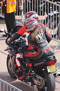 Motorcycle pillion passenger wearing a two-piece leather suit styled with a short jacket