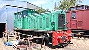 A green 0-6-0 diesel locomotive 'V8' sits on a track just outside of the workshops in queenscliff