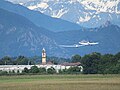 Aliante trainato da aereo in decollo; sullo sfondo, il campanile della Chiesa di Santa Croce di Collegno e la Sacra di San Michele.