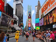Times square with people sitting on a bench and a costumed character