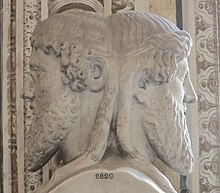 A stone bust of a man with two opposite facing heads, and curled beard.