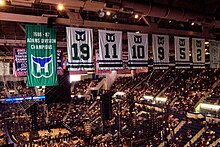 Photo de l'intérieur du Hartford Civic Center avec au premier plan, la bannière de champion de la division Adams 1986-87 des Whalers de Hartford et les 6 maillots retirés de ces mêmes Whalers : de gauche à droite, les numéros 19, 11, 10, 9, 5 et 2.