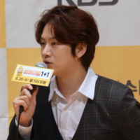 Kim Hee-chul speaking into a microphone and facing left