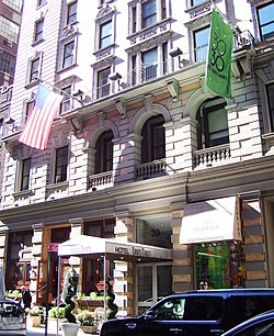 View of the Martha Washington Hotel as seen from across 30th Street. The facade is made of brick and stone, with large ground-story windows and doorways.