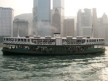 double-decker ferry boat in harbour with tall buildings in background