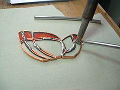Pieces of glass are wrapped in copper tape and then soldered.