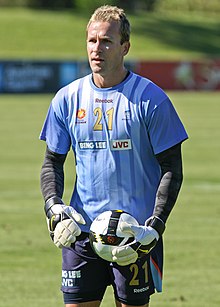 Clint Bolton, wearing a blue shirt, a black undershirt and white gloves, standing on a football field