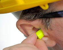 A man inserting an earplug in his ear to reduce the noise exposure Man inserting earplugs.jpg