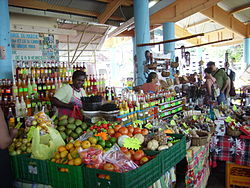 Vendor selling numerous types of fruit, vegetables and beverages.