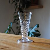 A Georgian ale glass from the around the mid-18th century. It has wrythened gadrooning to the lower half of the bowl.