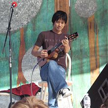 Shimabukuro seated and playing ukelele