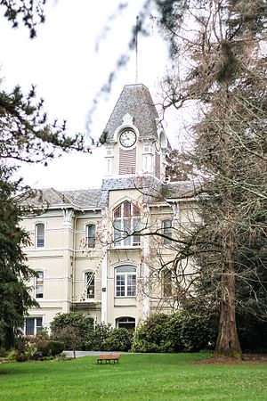 Front view of the building's exterior showing all three floors and the dense landscaping surrounding it