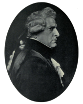 Right profile of stern-faced man in dark clothing with lacy shirt and cuffs, wearing a wig