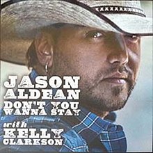 An image of a man wearing a white cowboy hat, looking aside. He is wearing a blue shirt and his right ear is pierced. Next to him the words "Jason Aldean Don't You Wanna Stay" and "with Kelly Clarkson" are written in white color.